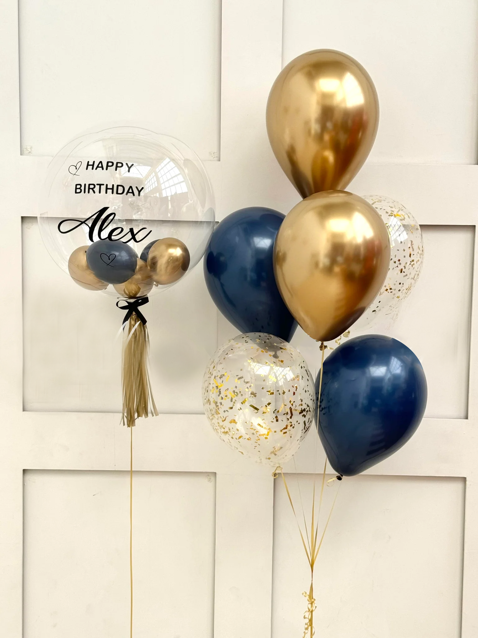 Decorative balloons with a 'Happy Birthday Alex' card on a white background