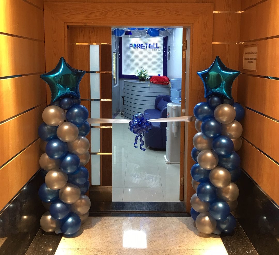 Decorative balloon arch with blue, silver, and gold balloons in front of a door with 'FORETEL' branding.