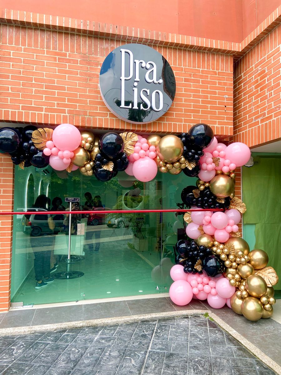 Decorative balloon arch in front of a building with 'Dra Liso' sign.