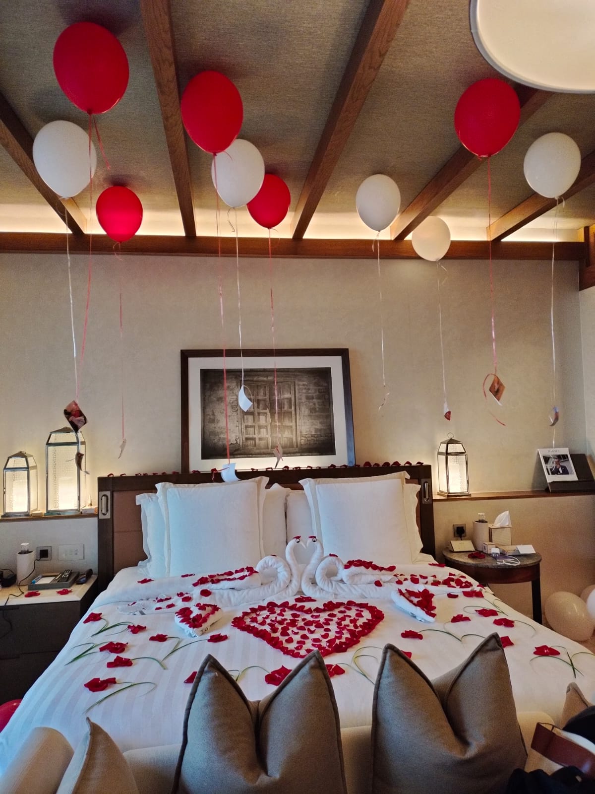 Decorated bedroom with heart-shaped bedspread, balloons, and swan decorations.