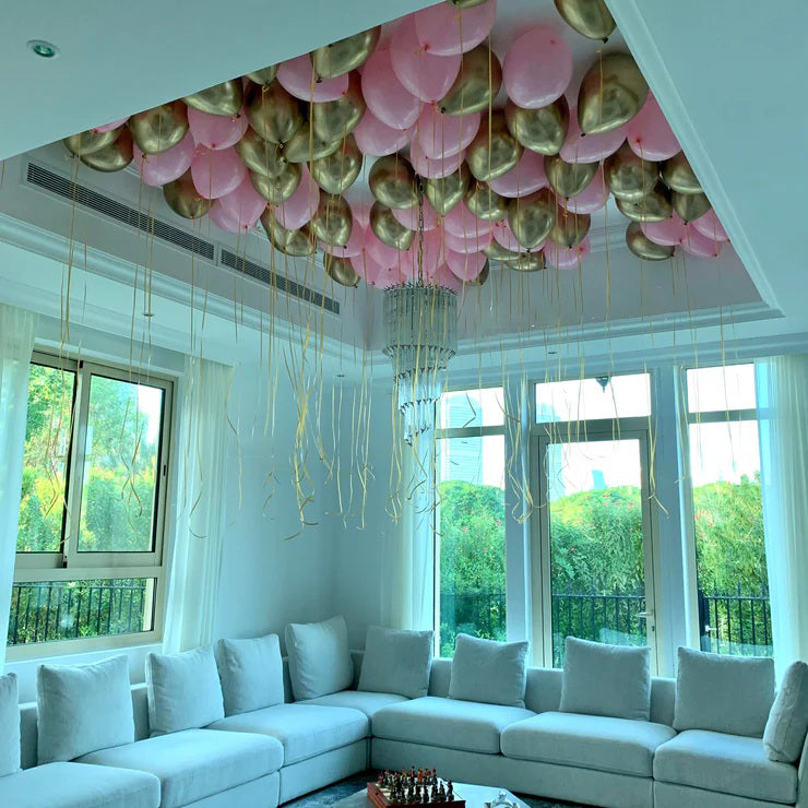 Living room with white sectional sofa and pink and gold balloons decorating the ceiling.
