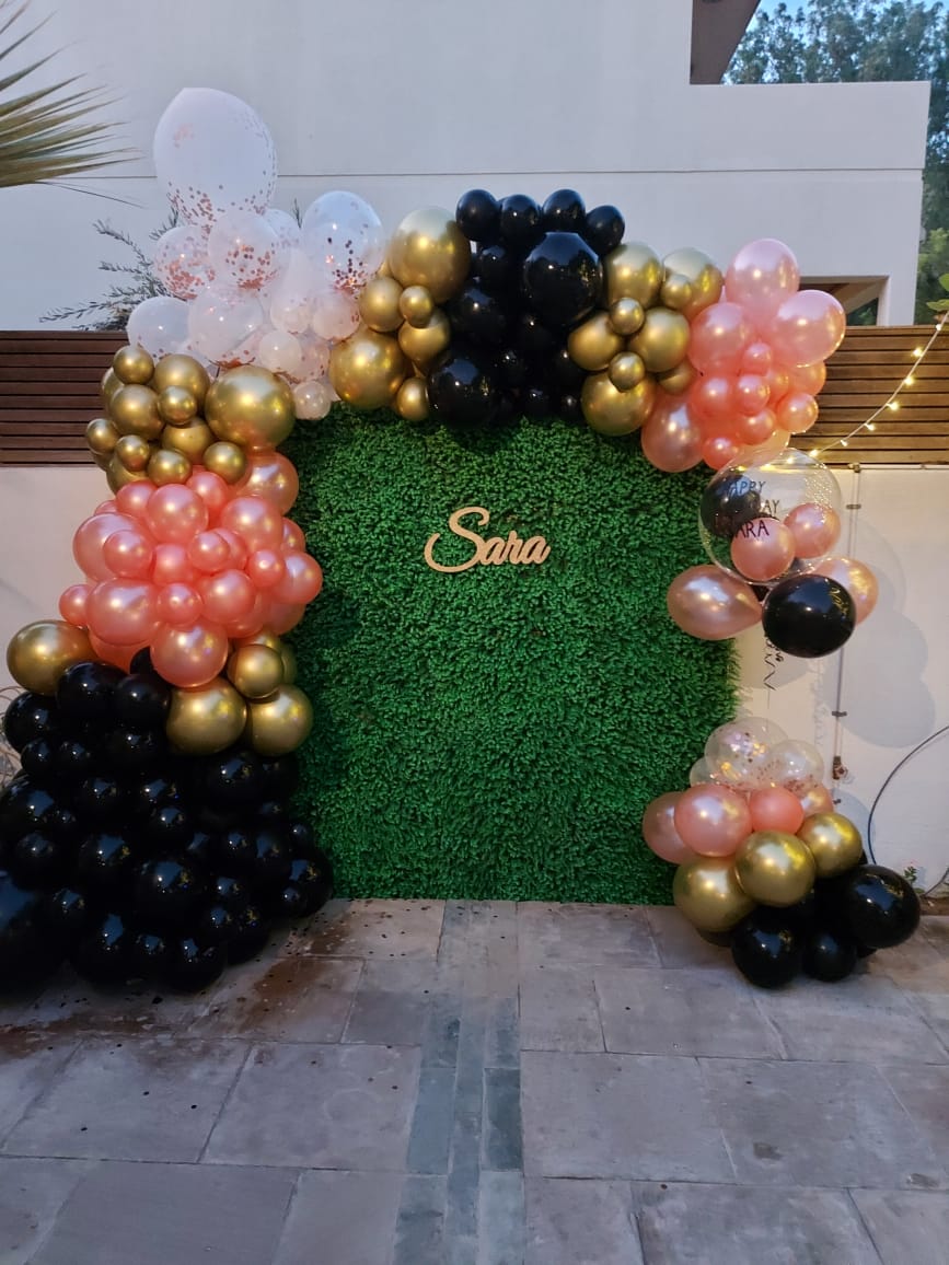 Decorative arch with balloons and 'Sara' text on a green background