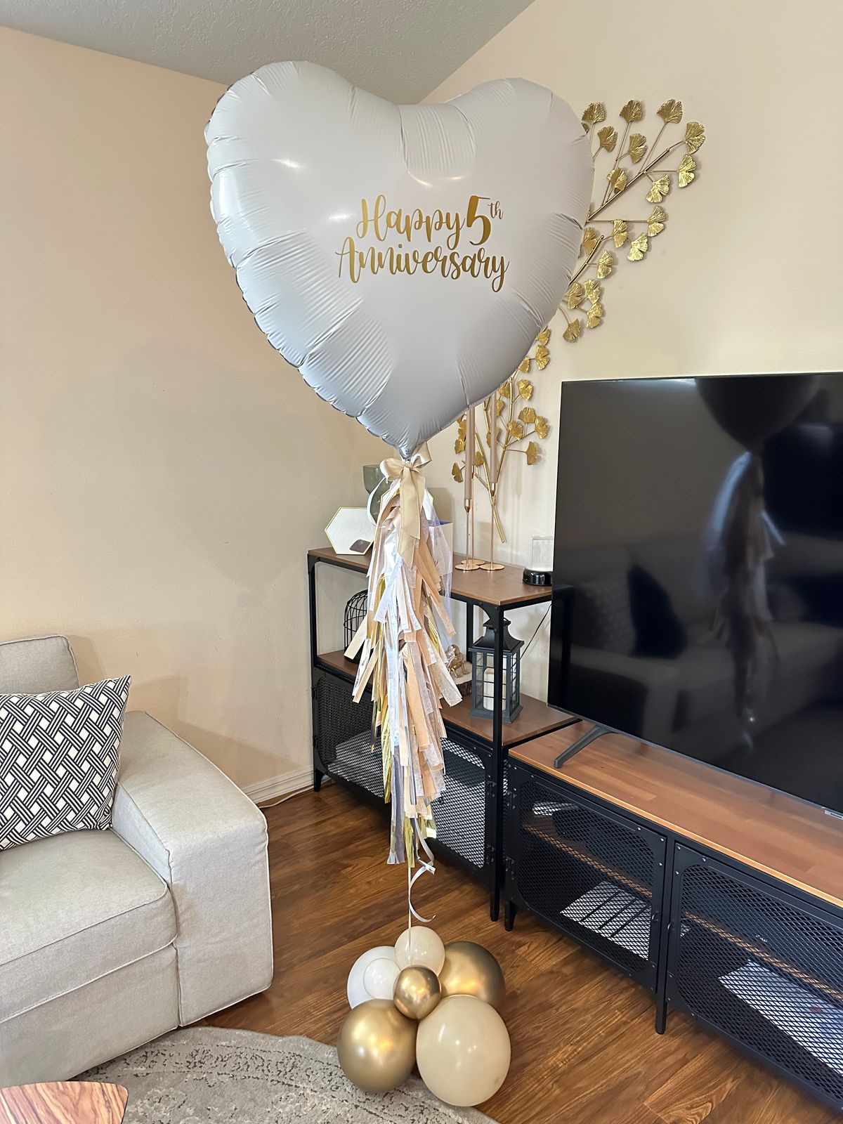 Heart-shaped balloon with 'Happy 5th Anniversary' text in a living room setting.