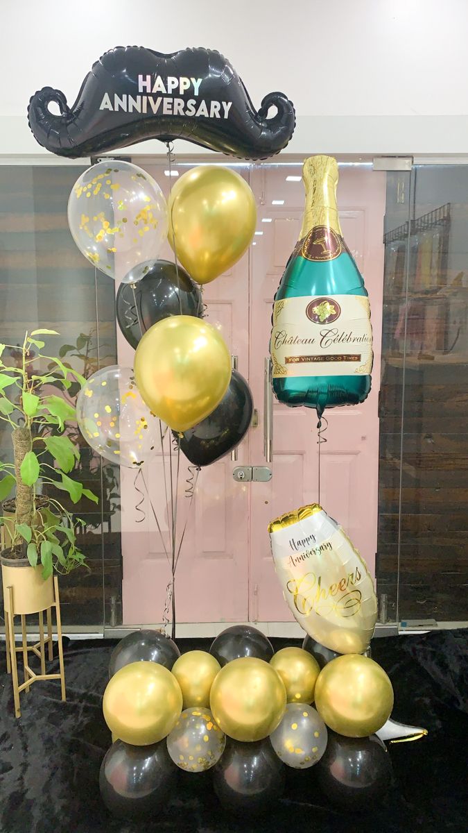 Decorative arrangement of balloons shaped like a bottle and glasses with 'Happy Anniversary' text.
