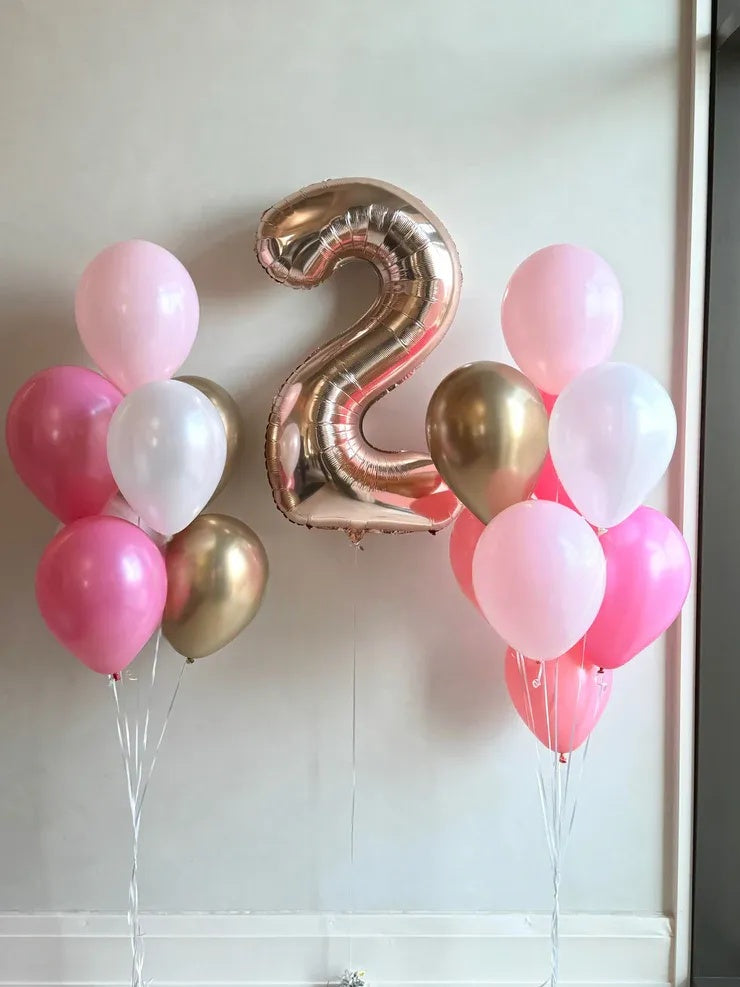 Balloon arrangement with a number '2' balloon on a white wall.