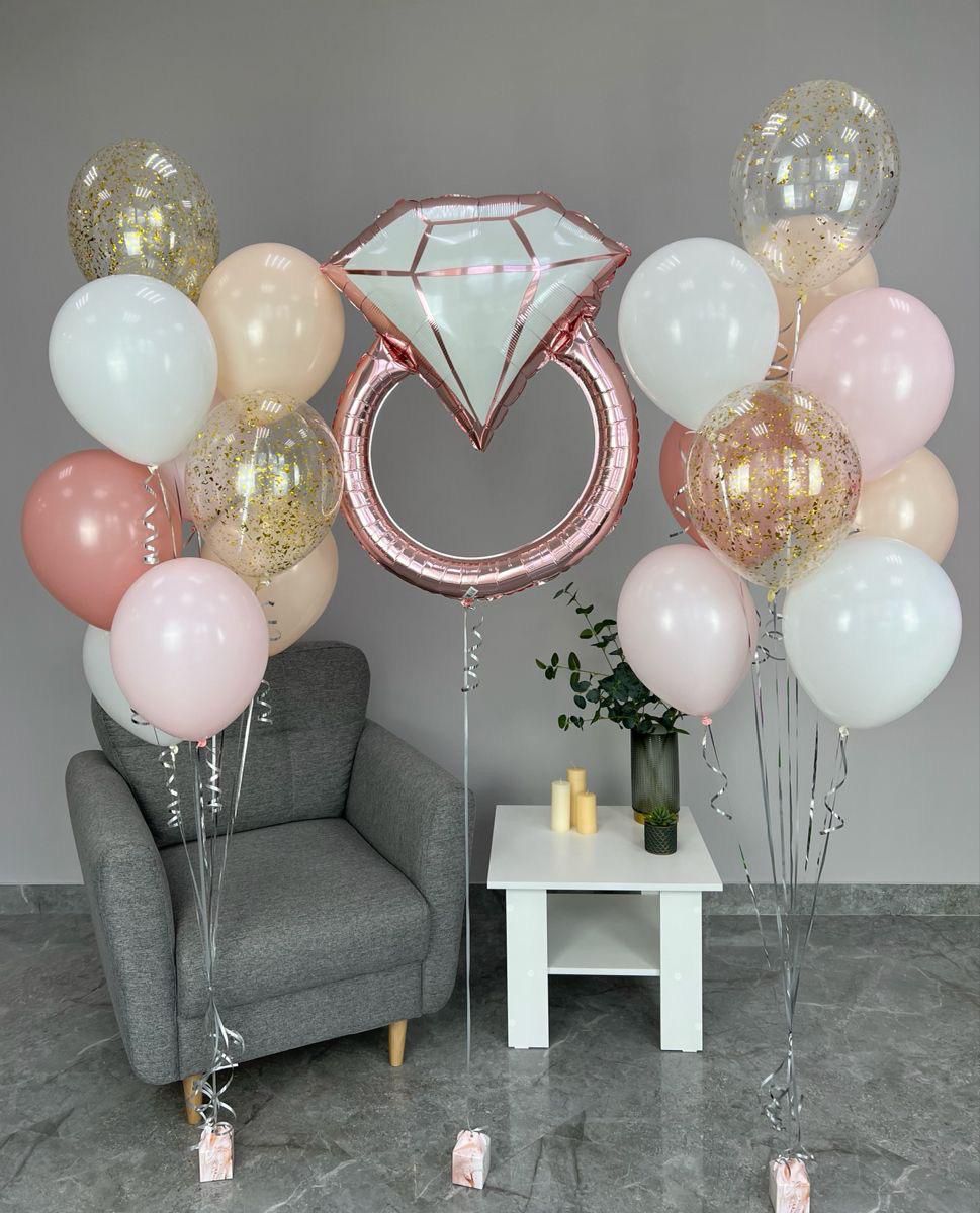 Decorative setup with balloons, a diamond-shaped balloon, and a small table with candles on a gray floor.